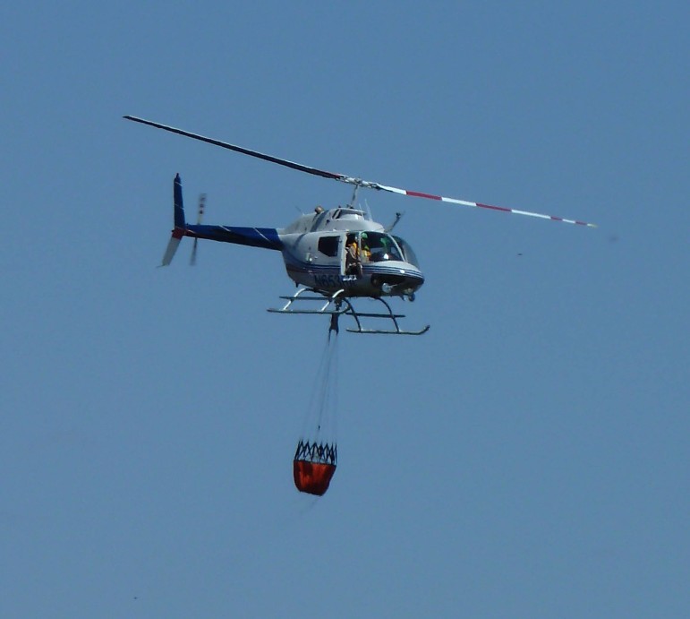 A helicopter drops water on a large brush fire in eastern Lower Saucon Township Wednesday afternoon.