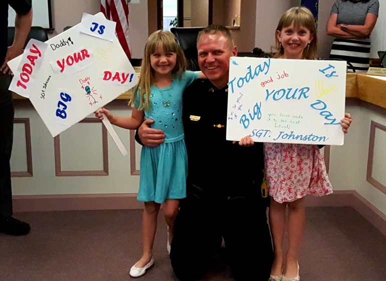 Sgt. Jeff Johnston of the Hellertown Police Department is flanked by his daughters after being promoted and sworn in. The girls made signs to congratulate their dad on his achievement.