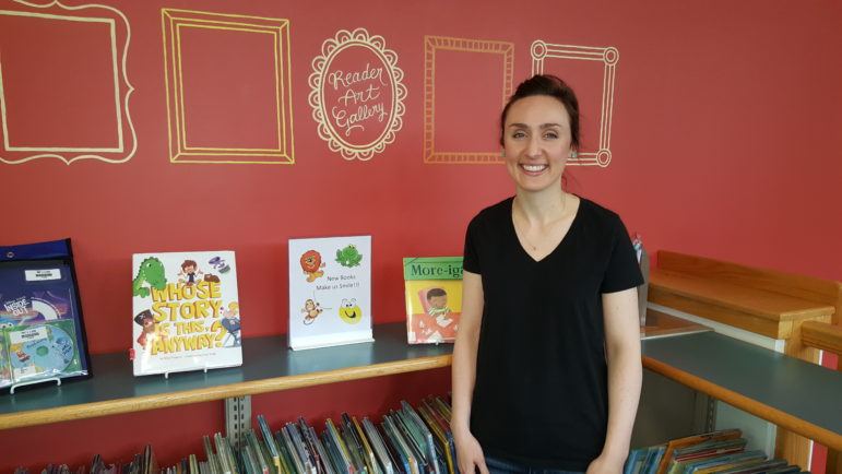 Artist Emily Graf of Hellertown stands in front of the Reader Art Gallery she created on one wall of the Hellertown Area Library's children's area.