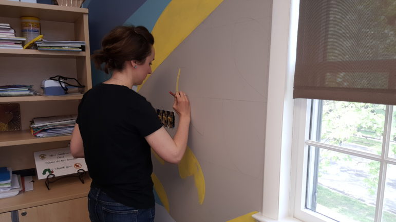 Emily Graf works on one section of a large mural on the second floor of the Hellertown Area Library.