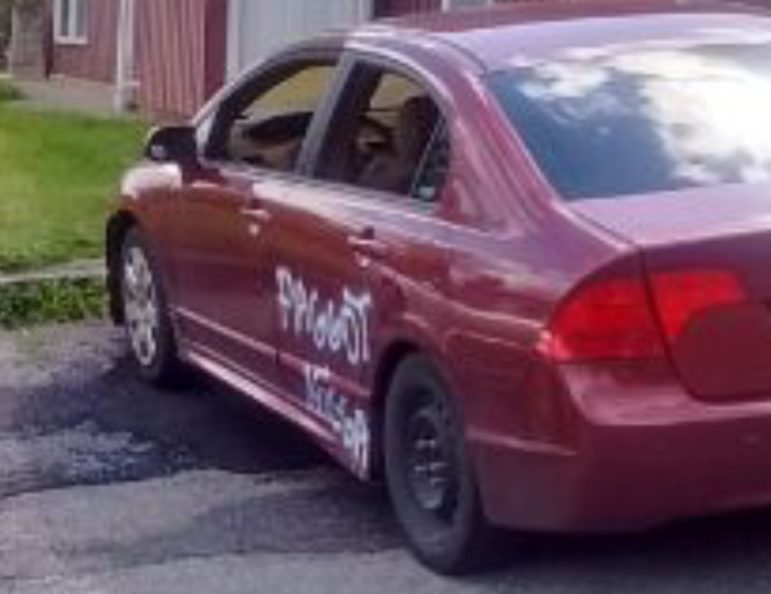 A photo of the car that burned in the Scenic View Apartments May 14 shows racial and homophobic epithets spray-painted on it.