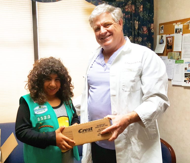 Dr. S. Clarke Woodruff, DDS, of Hellertown, presents Girl Scout Charisma Levens-Oyer with a box of Crest toothpaste and other oral hygiene items that will be donated to families in need.
