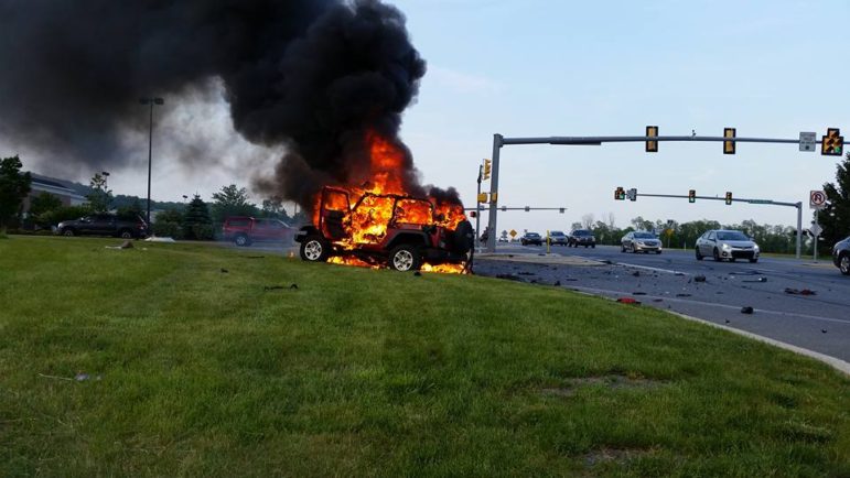 A Jeep burns near an entrance to the Promenade Shops at Saucon Valley in Upper Saucon Township following a violent accident on Center Valley Parkway on May 26, 2016.