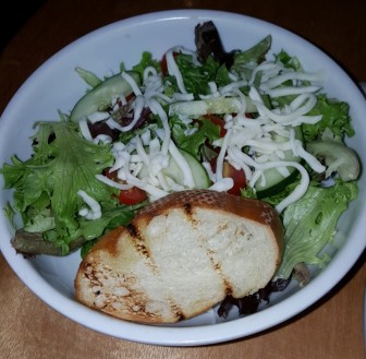 A house salad at Sagra features shredded cheese and a piece of toasted bread. It is served with a choice of dressing. (FILE PHOTO)