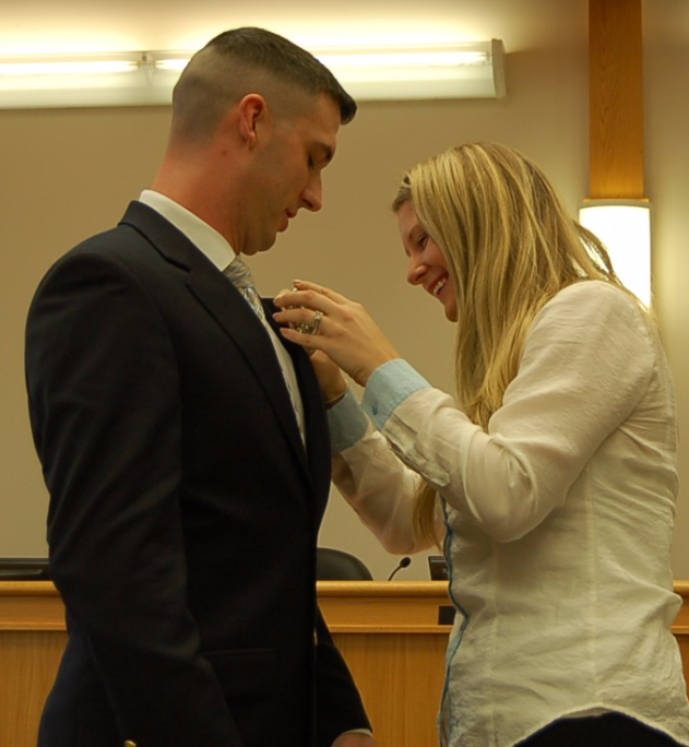 Ofc. Giorgi's wife Morgen pins his badge on his lapel at a swearing in ceremony at Lower Saucon Town Hall Thursday.