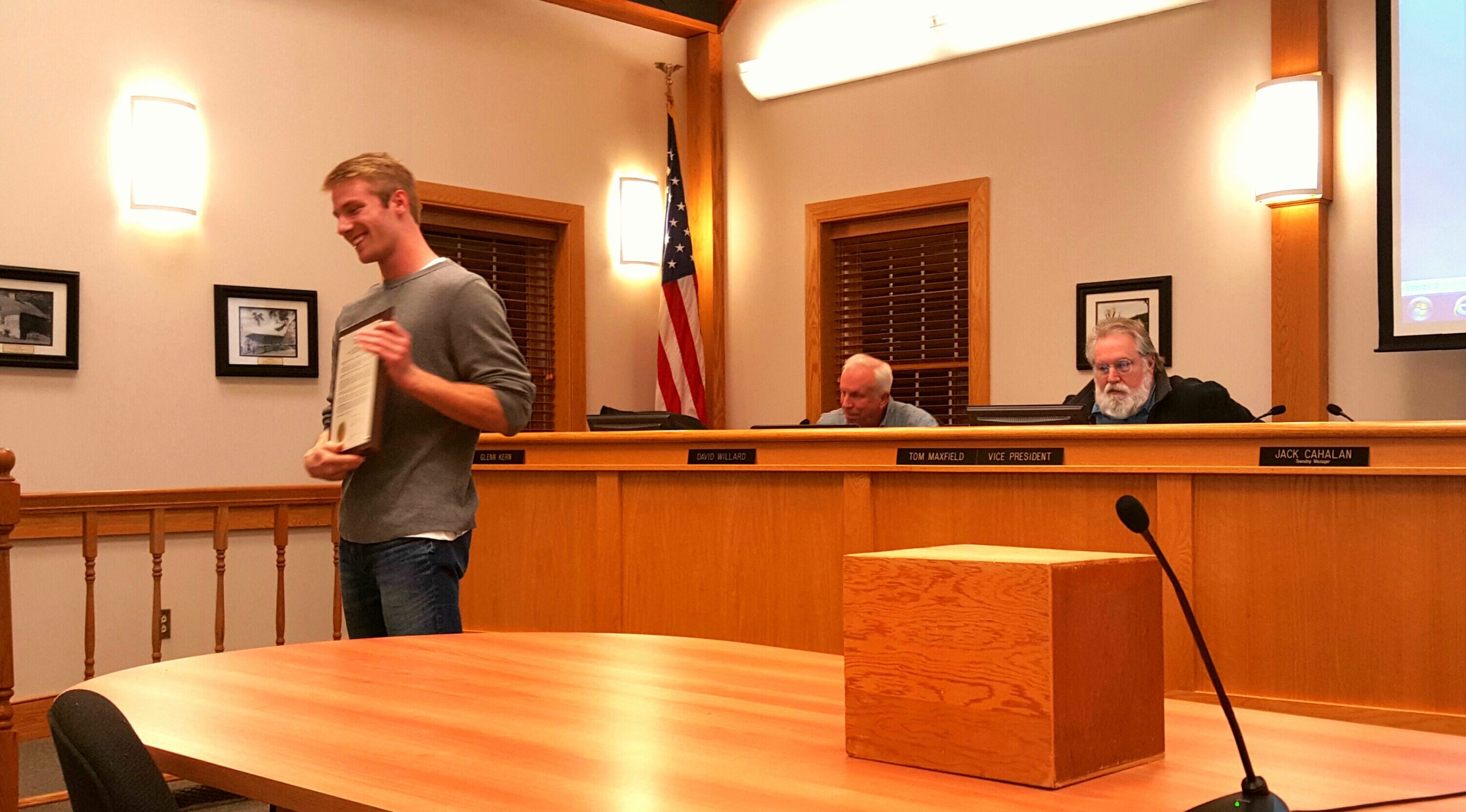 Zach Thatcher presents the resolution plaque to audience members after receiving it from Lower Saucon Township Council.