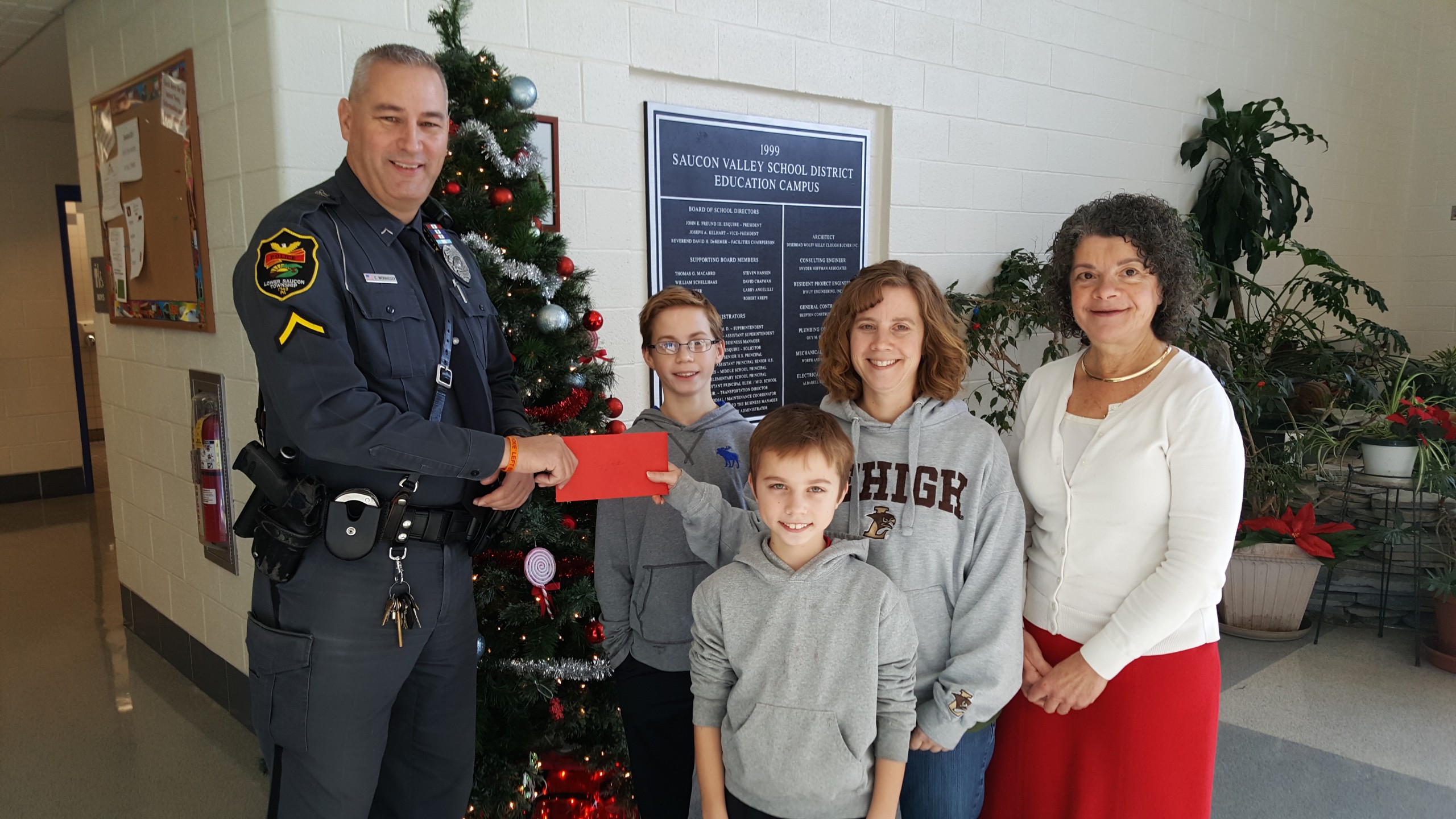 Ofc. Chuck Werkheiser of the Lower Saucon Township Police Department presents a gift to the Roseman-Gilly family at Saucon Valley Middle School. Pictured at right is middle school principal Pamela Bernardo.