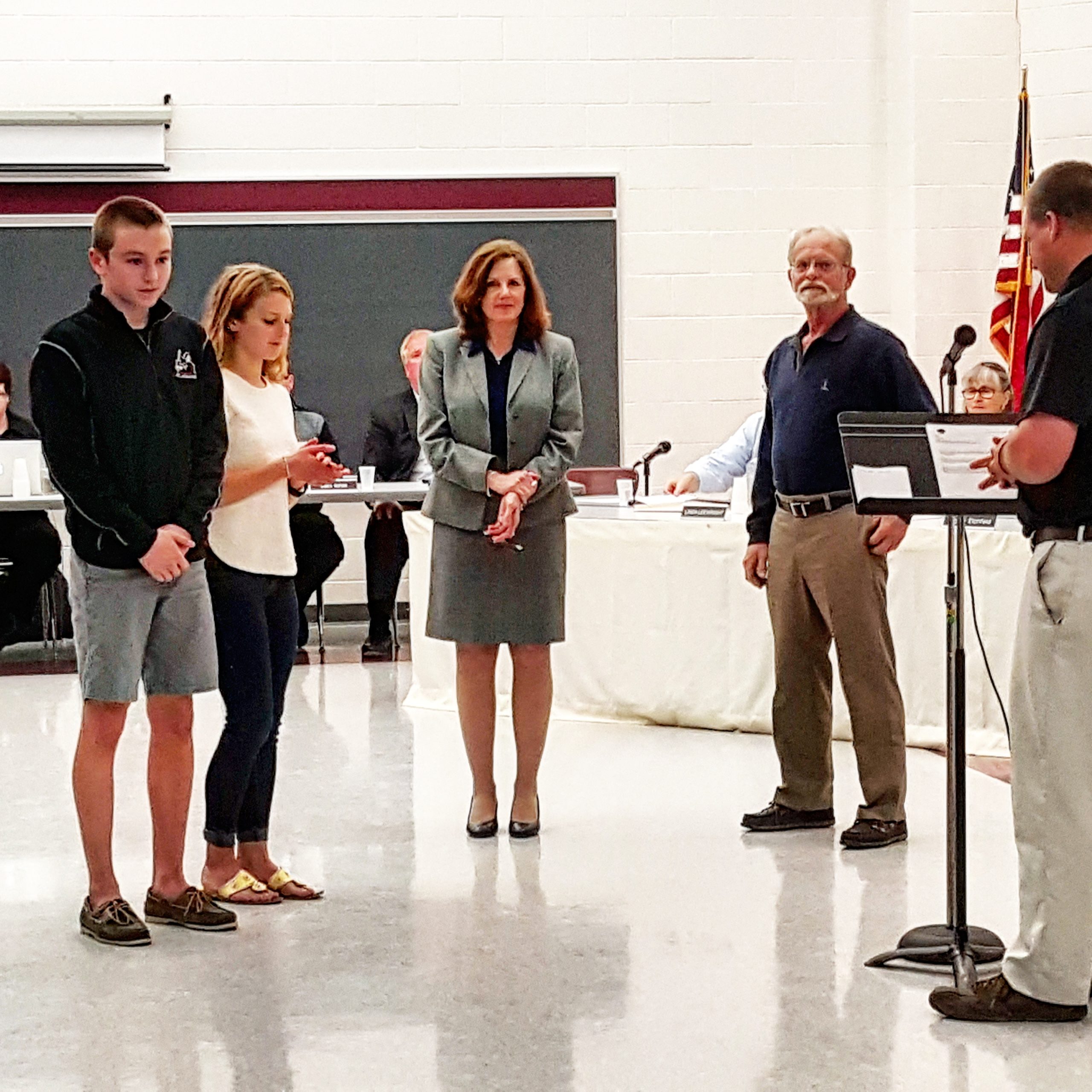 Top swimmers Tommy and Caroline Madigan are recognized at the school board meeting by Athletic Director Bob Frey (right), as Supt. Dr. Monica McHale-Small and school board President Michael Karabin look on.
