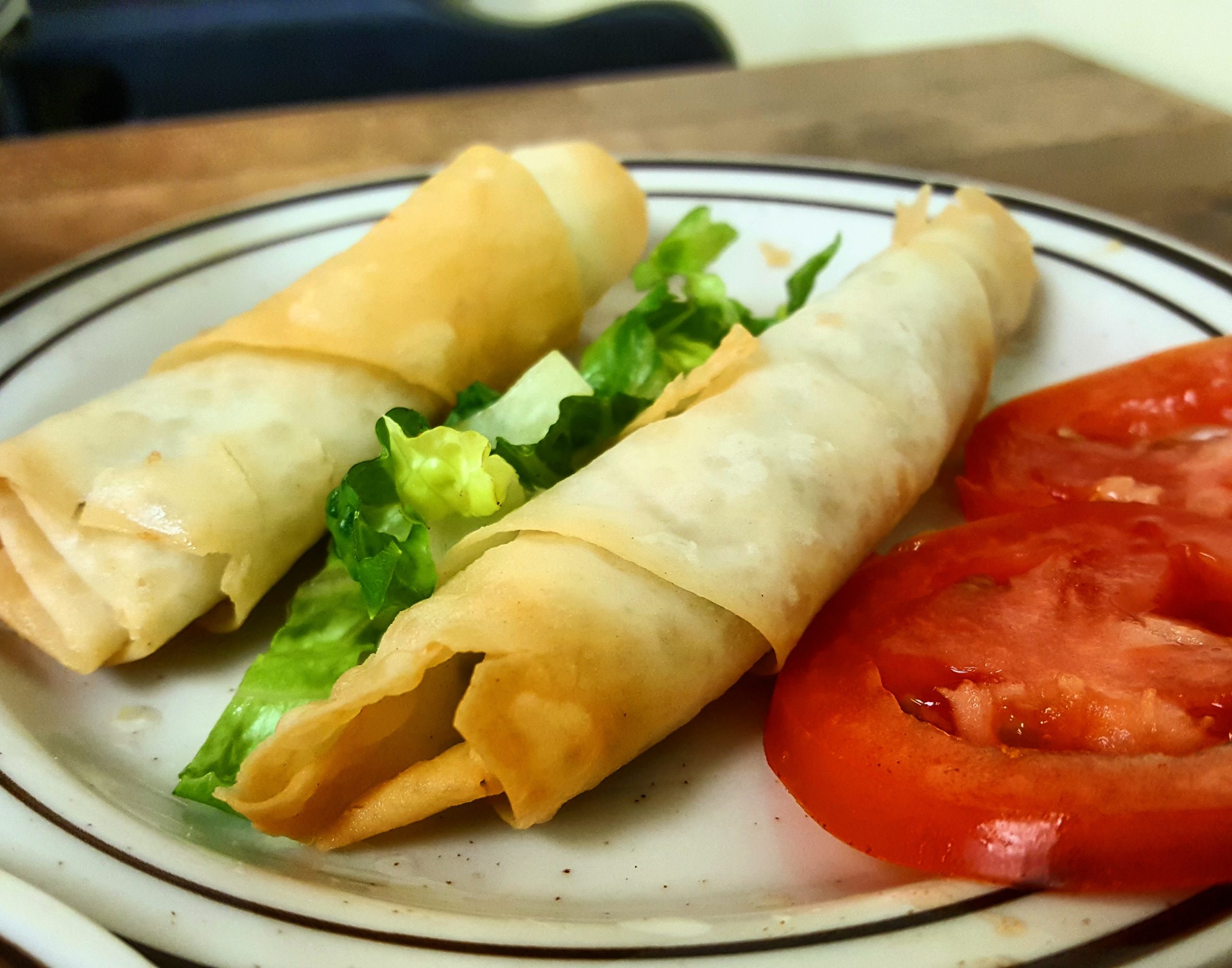 A fried cheese appetizer is served with fresh lettuce and tomato.