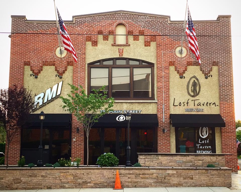 The renovated exterior of the RMI building includes an outdoor seating area, awnings and signage for Lost Tavern Brewing.
