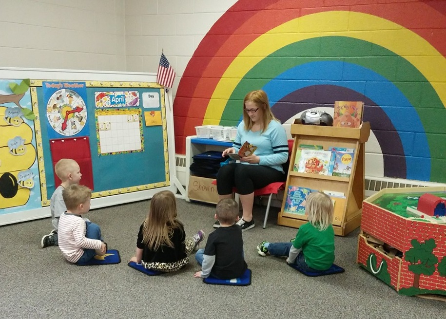 A "Mystery Reader" reads a story to Apple's Preschool students.